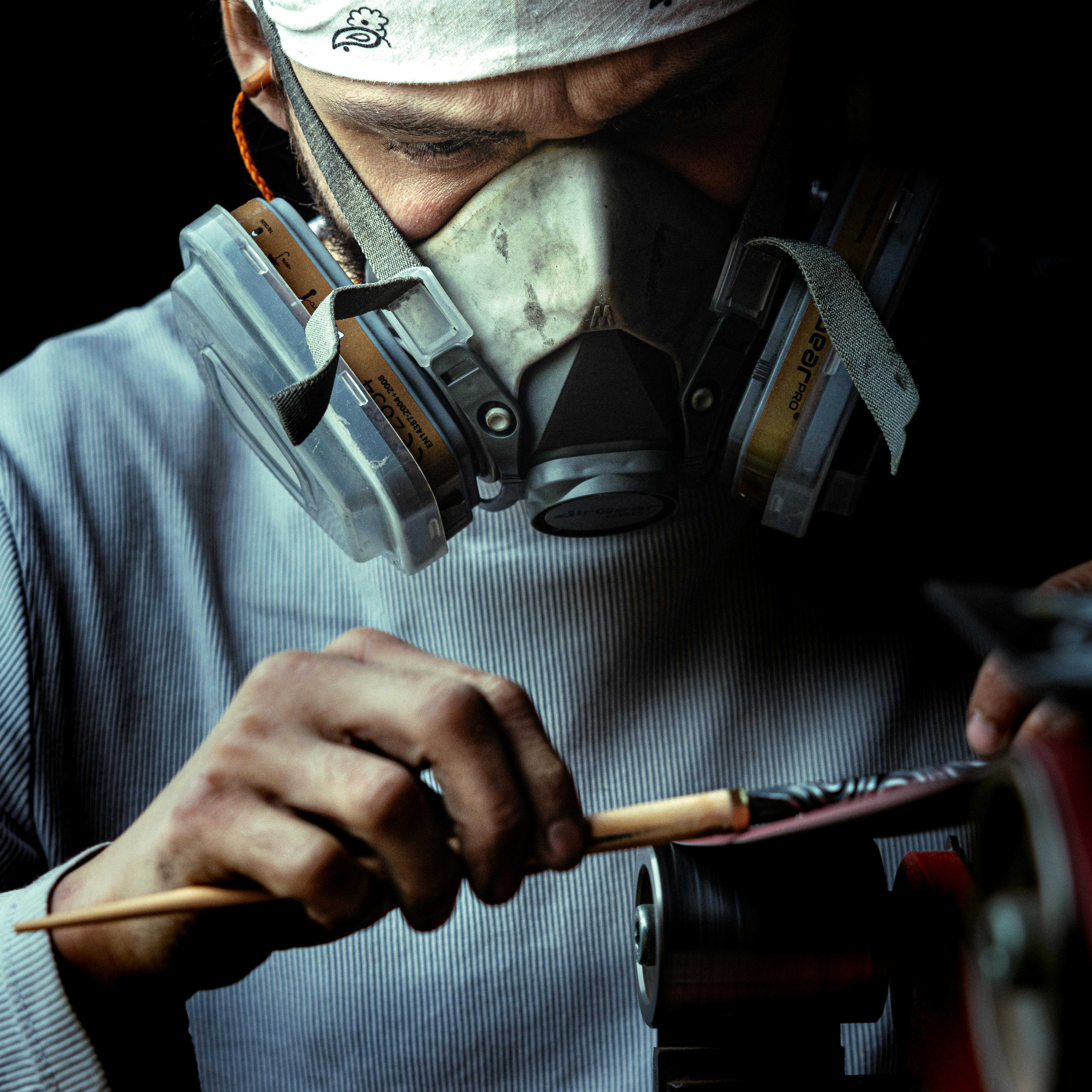 Close-up of a masked artisan carefully crafting with tools, showcasing skill and precision.