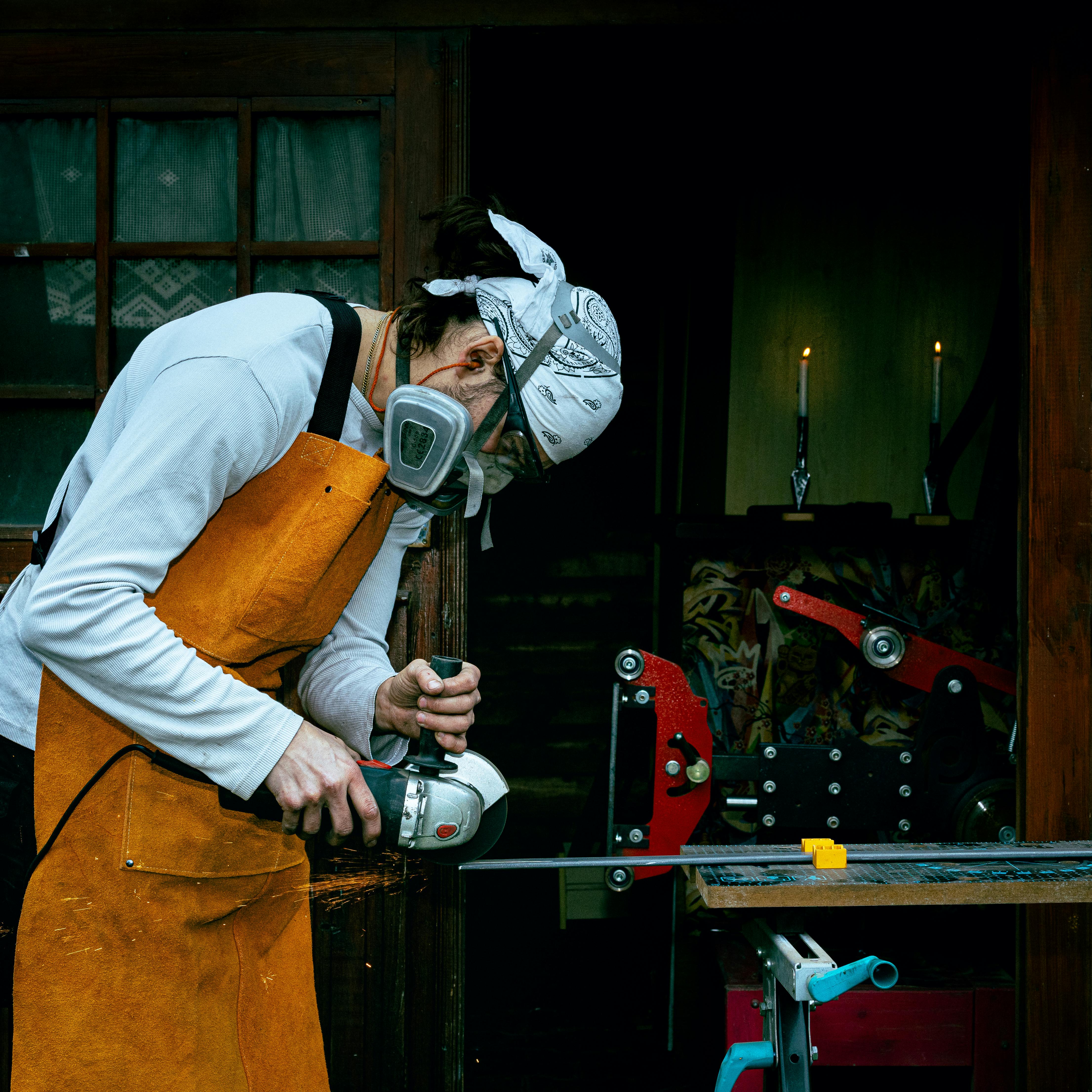 Artisan using grinder in workshop, showcasing craftsmanship and dedication to metalwork.