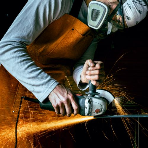 Free A craftsman using an angle grinder in a workshop, creating vibrant sparks. Stock Photo