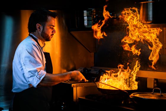 Chef finishing a dish over open flame. Photo by Alex Grandidier on Pexels