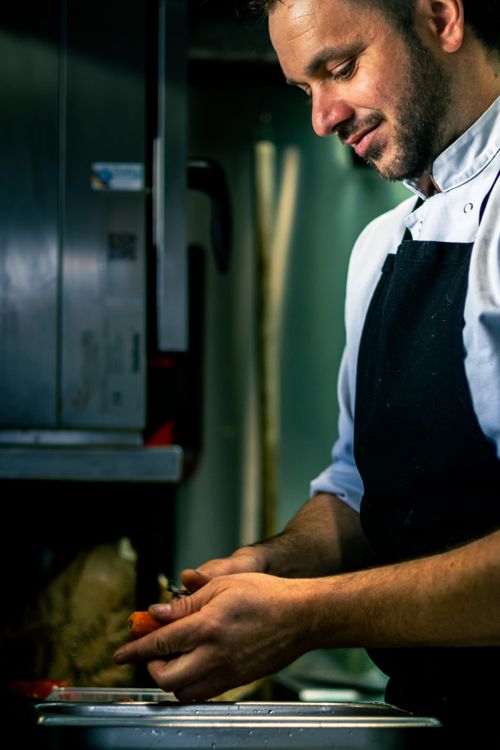 Free Chef preparing carrots in a Bayonne kitchen, showcasing culinary art and expertise. Stock Photo