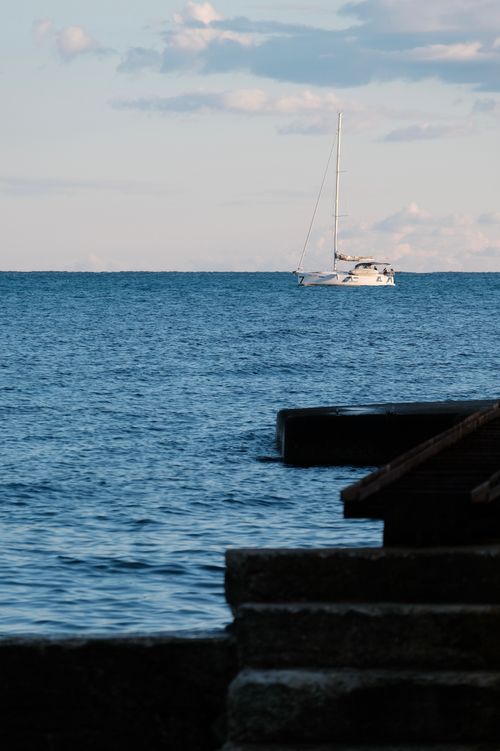 Free Sailing boat floating on tranquil ocean with clear sky and gentle waves. Stock Photo
