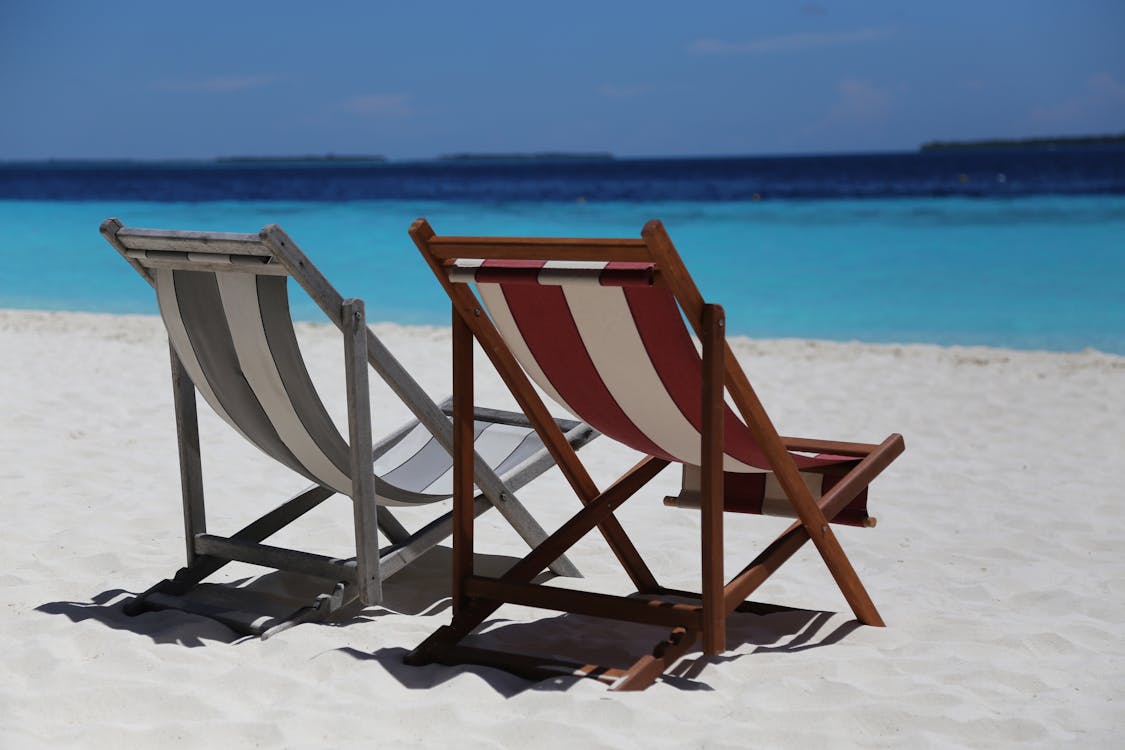 Two Folding Chairs on White Sand Seashore