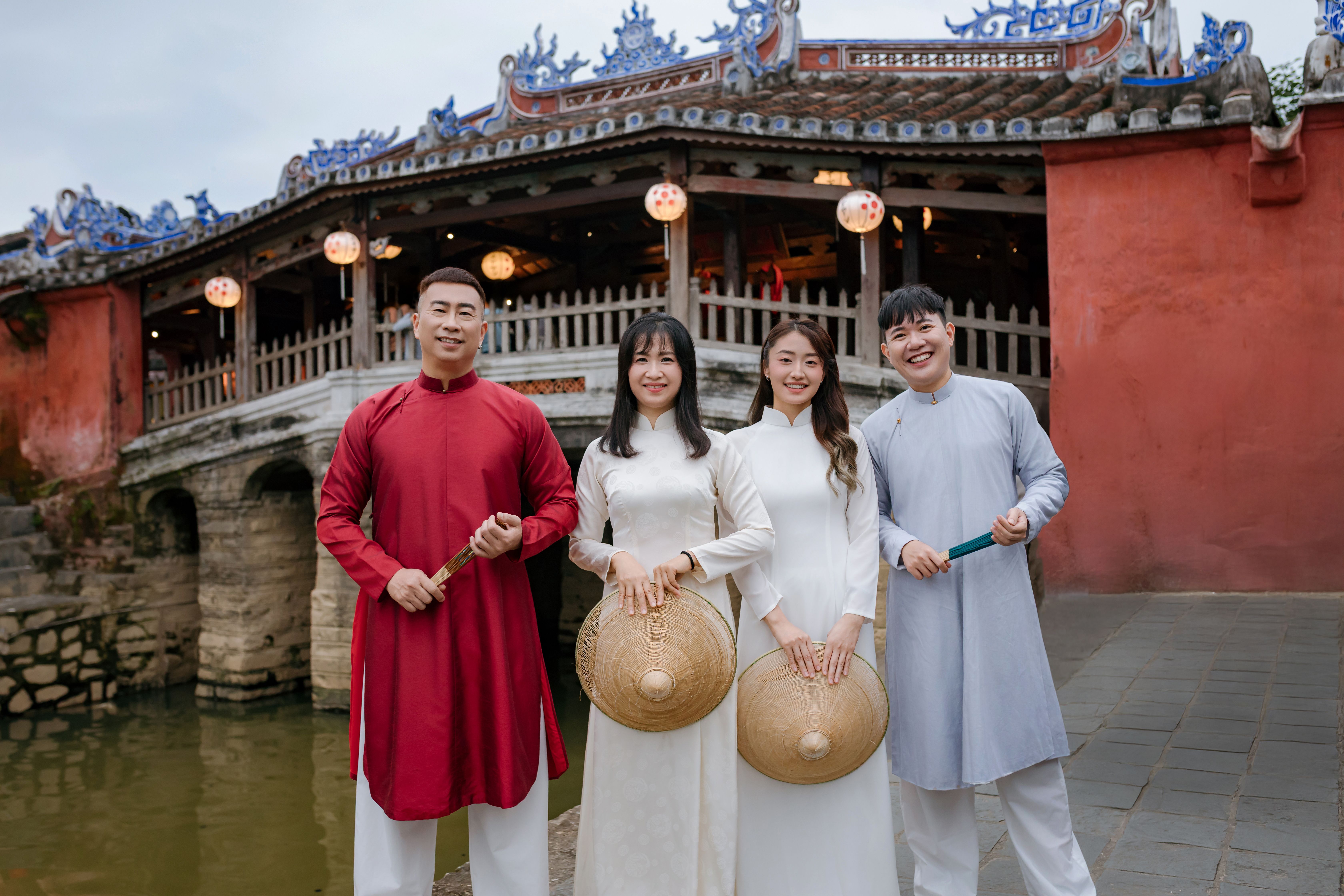 Group in traditional Vietnamese attire near Hoi An's historic Japanese Bridge.