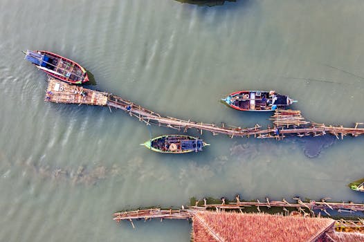 A stunning aerial view of traditional fishing boats docked on a wooden pier in Banten, Indonesia.