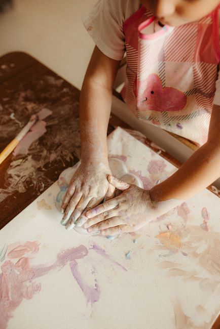 A child engaging in artistic expression with colorful paints indoors.