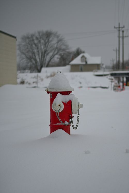 Free A lone red fire hydrant stands in a snow blanketed field during winter. Stock Photo