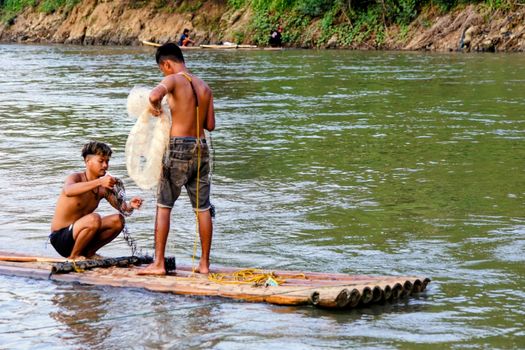 Two young men fishing with nets on a river in Cianjur, Indonesia, capturing traditional life.