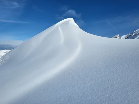 Stunning view of a snow-covered mountain peak against a bright blue sky, showcasing nature's beauty.