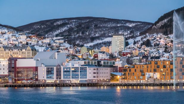 Captivating winter cityscape featuring colorful buildings by a snowy waterfront at twilight.