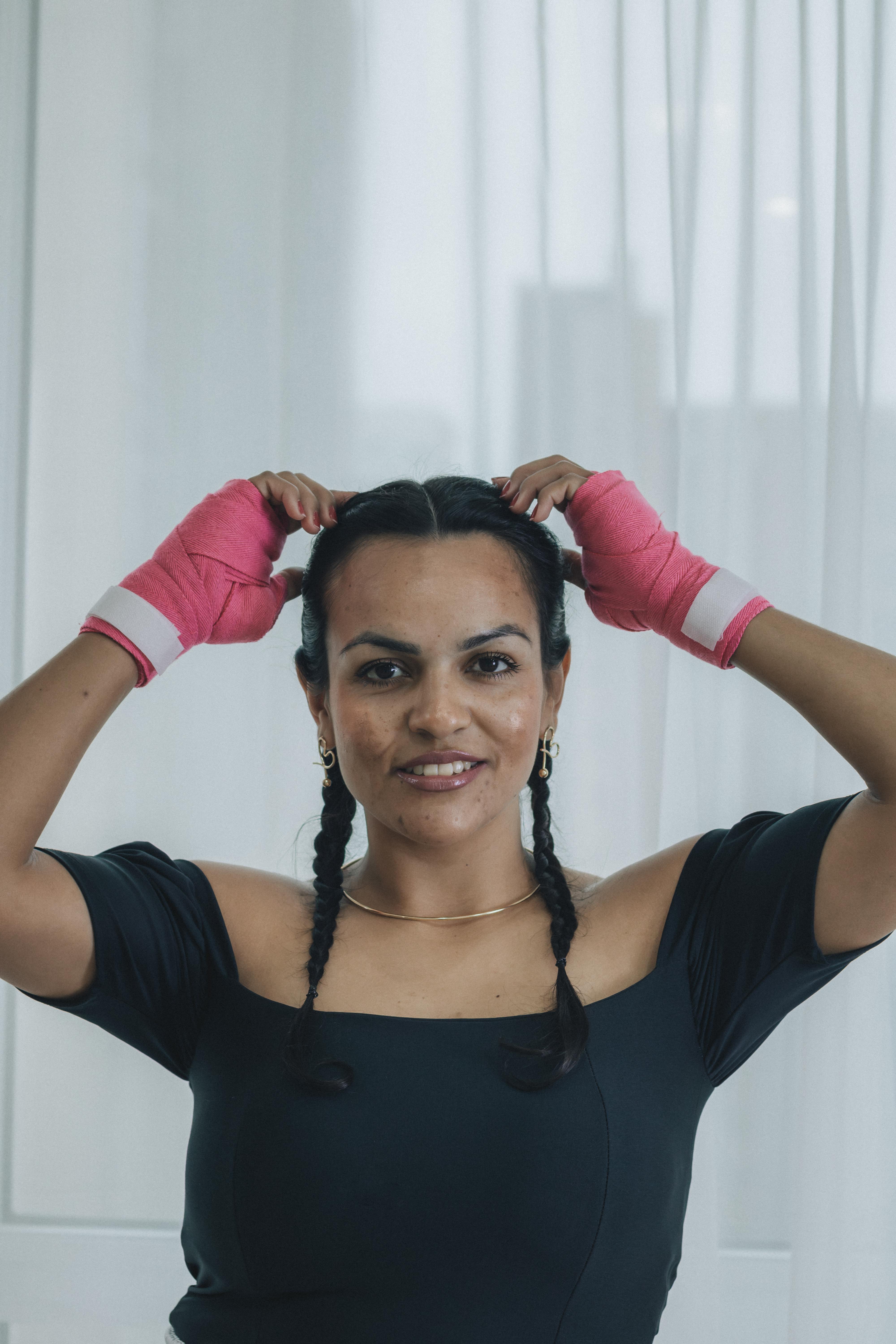 De franc Retrat d'una dona a l'interior, amb mantells de boxa roses i cabells trenats, que traspua confiança. Foto d'estoc