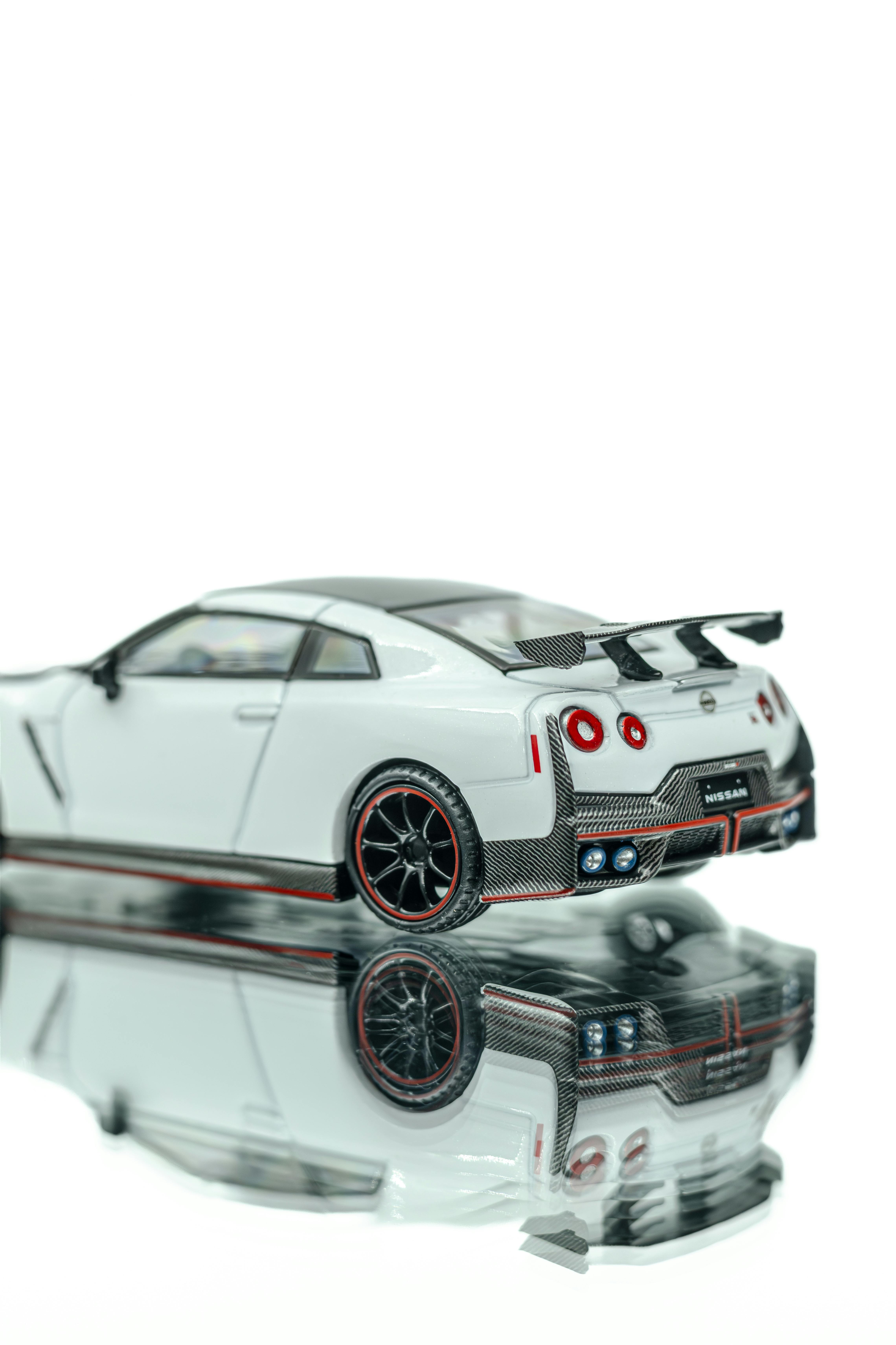 Gratis Tampilan jarak dekat dari model mobil yang detail di atas permukaan reflektif yang menyoroti desain dan fitur-fiturnya. Foto Stok