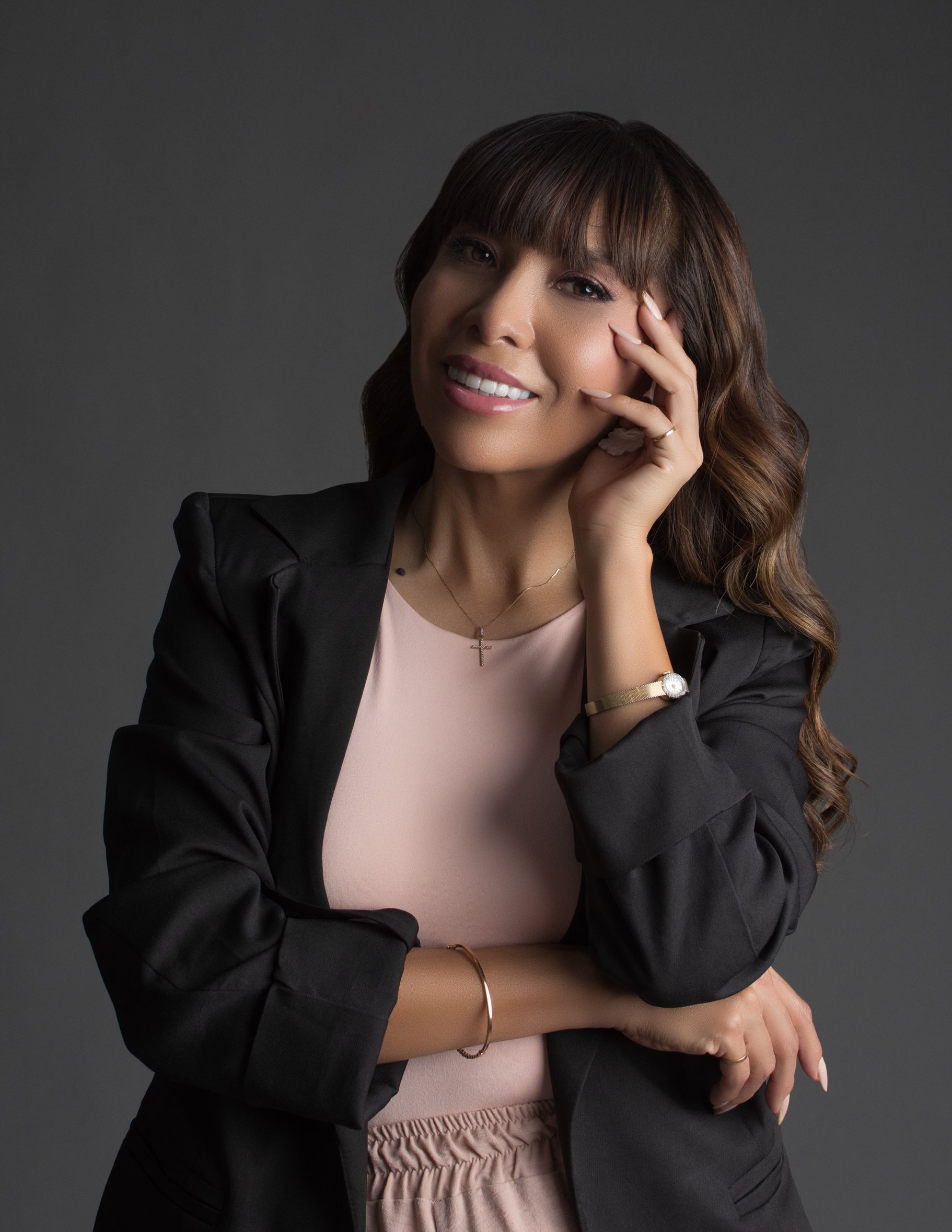 Portrait of a confident woman in a black blazer and pink top, showcasing elegance.
