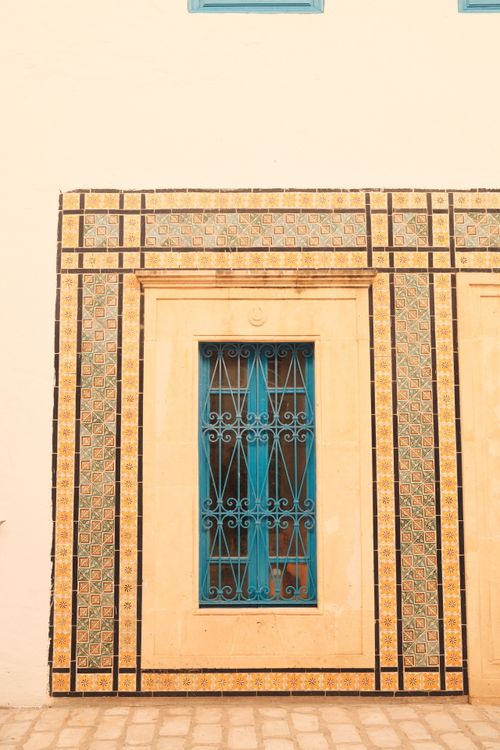 Free Beautiful Tunisian facade featuring ornate blue door and intricate tile work in warm tones. Stock Photo