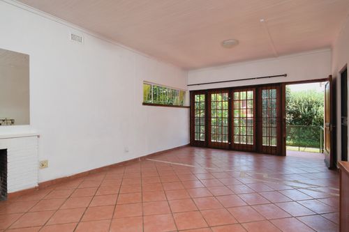 Free Bright empty room with tile flooring, white walls, and French doors leading to a garden. Stock Photo