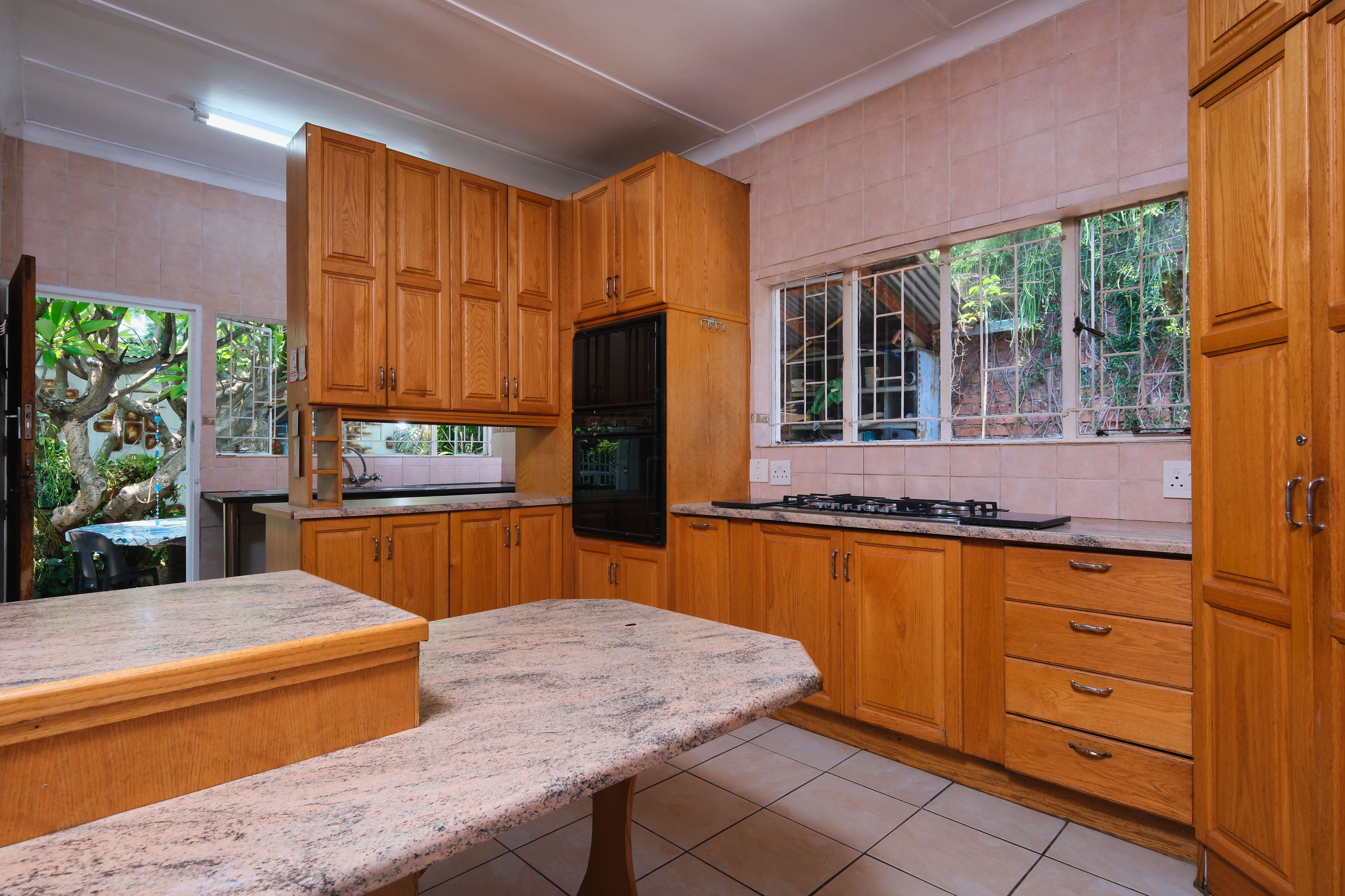 Warm kitchen with wooden cabinets and marble counters after a home addition in Kitchener.