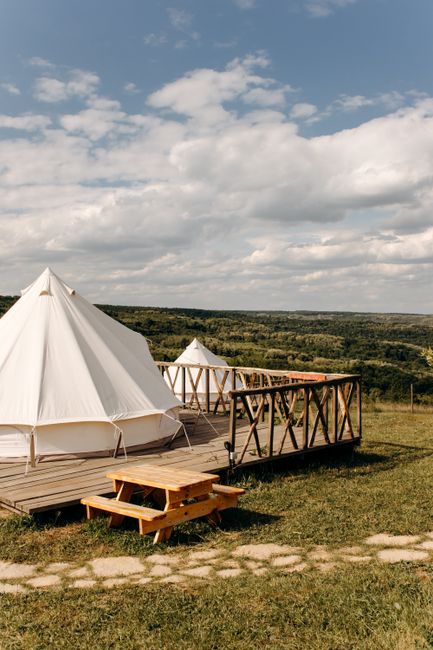 Explore a serene glamping site with pristine tents and a vast open landscape under a bright sky.