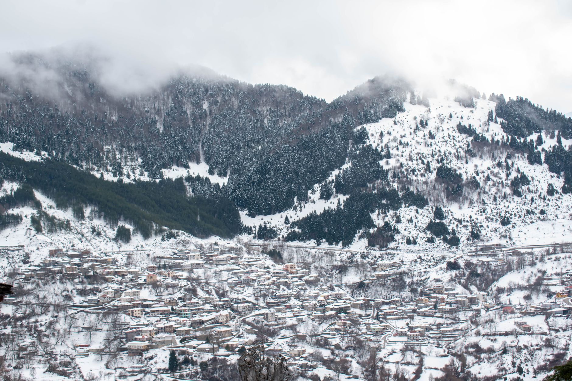 Metsovo's stone and wood mountain houses on a steep slope with Pindos peaks behind