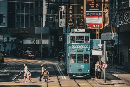 Free A vibrant street scene in Hong Kong featuring a historic tram, pedestrians, and iconic urban buildings. Stock Photo