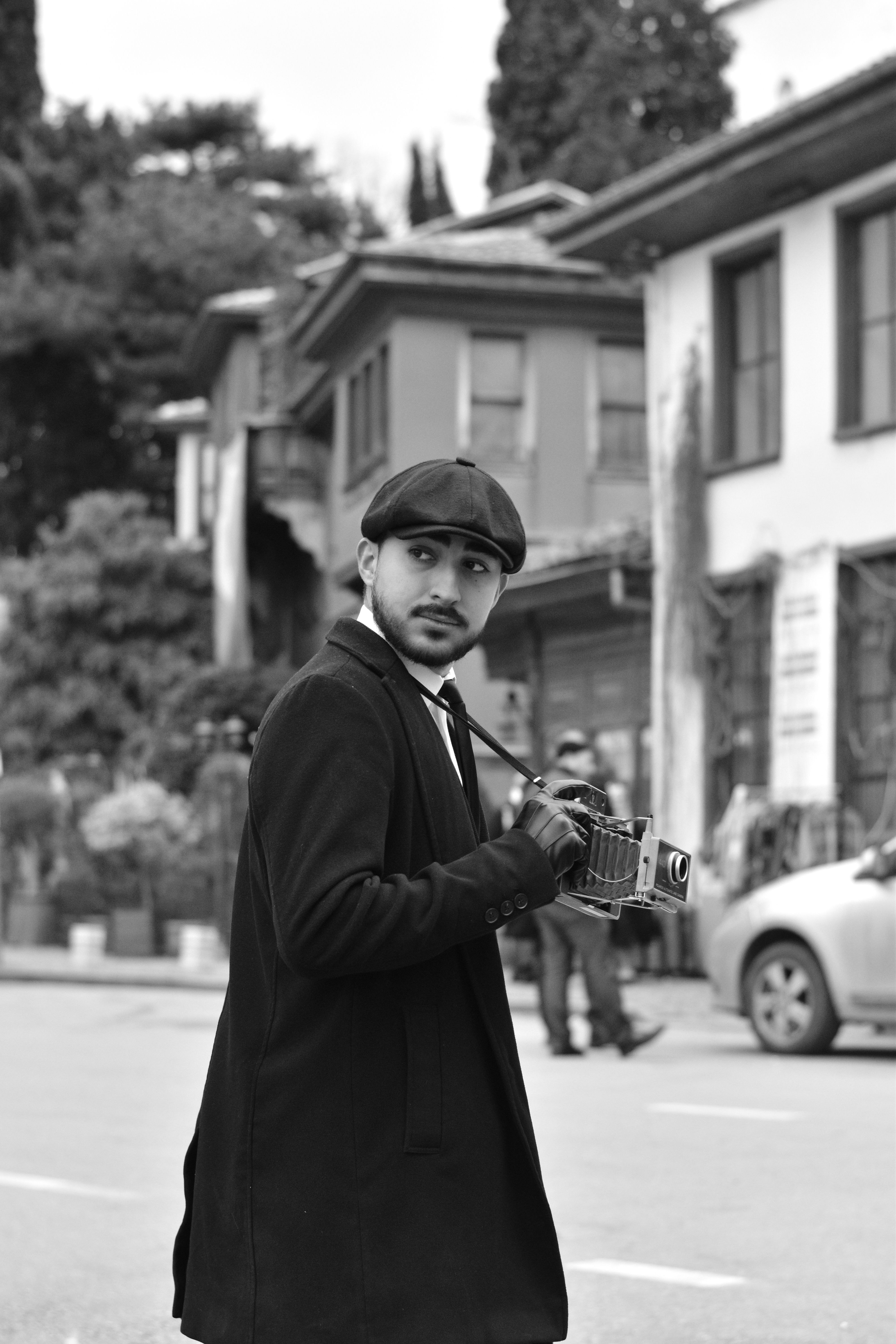 Retro-inspired street portrait of a man with vintage camera in historic Bursa, Türkiye.