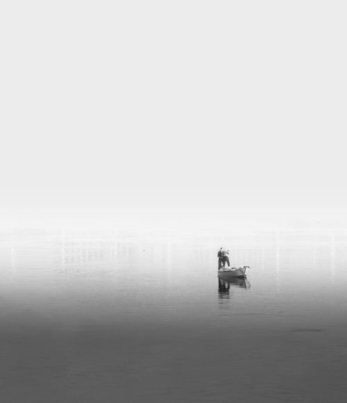 Free A lone fisherman in a boat on the misty Nile River creates a serene scene. Stock Photo