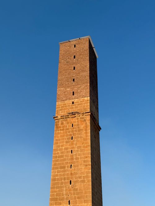 Free A historic stone tower stands tall against a clear blue sky in Mardin, Turkey. Stock Photo