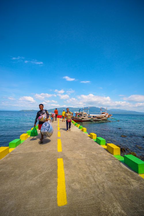 Free Vibrant pier scene with people in tropical setting by the ocean. Stock Photo