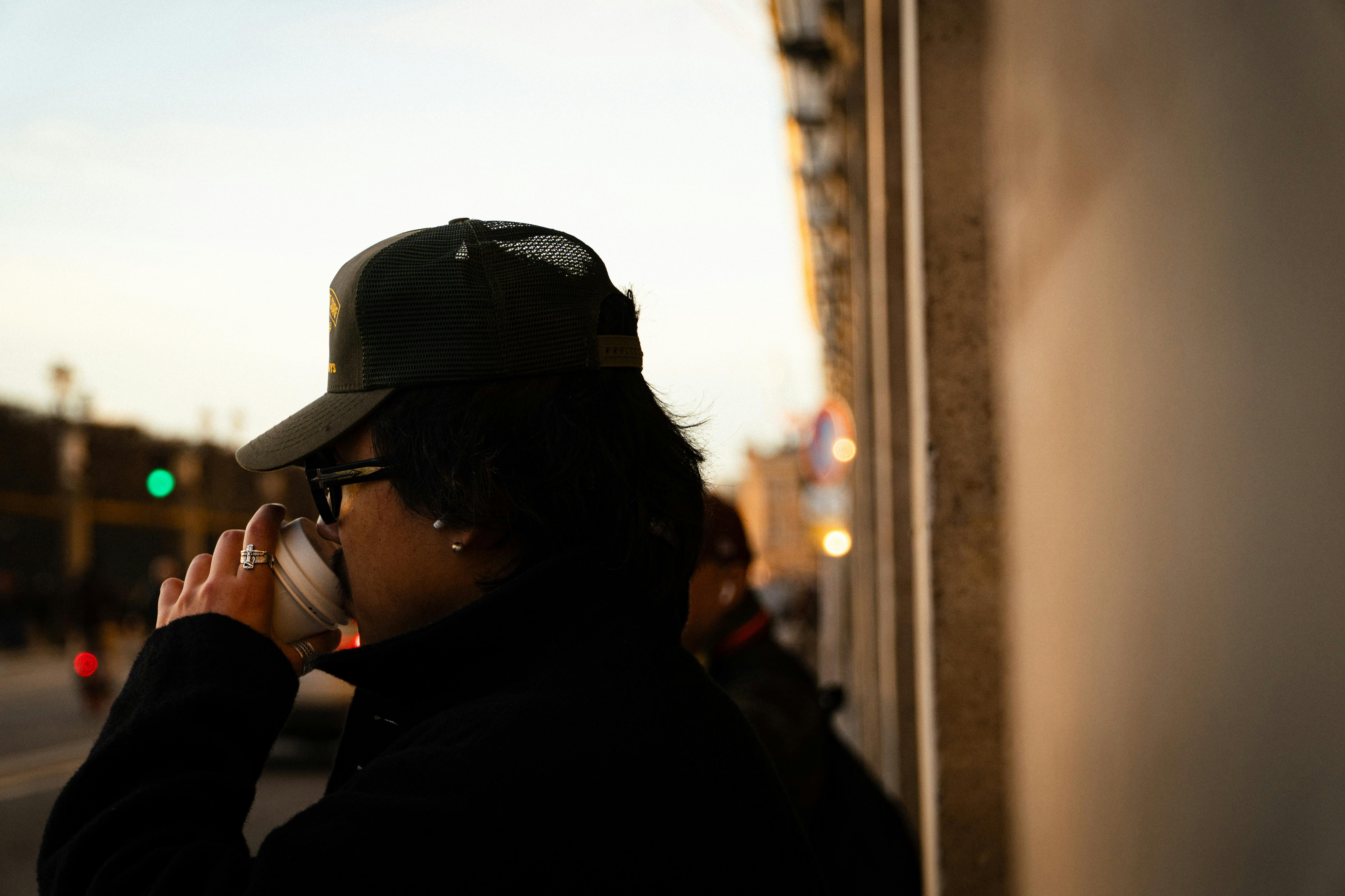 De franc Home amb gorra i ulleres de sol prenent cafè en un carrer parisenc a la posta de sol. Foto d'estoc