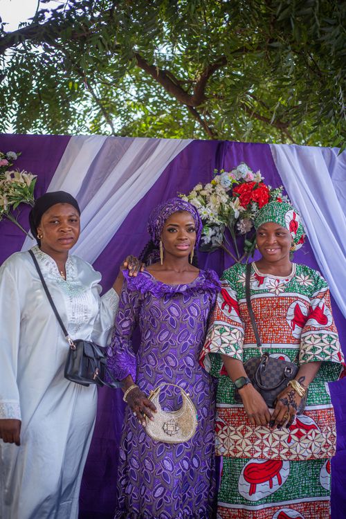 Free Three women in vibrant traditional African attire pose outdoors with colorful drapes. Stock Photo