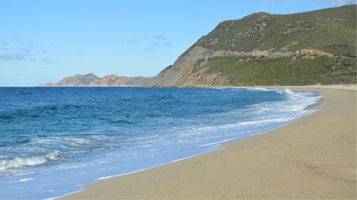 Free Beautiful sandy beach with turquoise sea and mountains in Belgodère, Corsica. Stock Photo