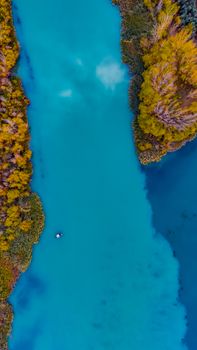 Aerial view of a turquoise river flanked by autumn foliage in Adıyaman, Türkiye, capturing a tranquil and scenic setting.