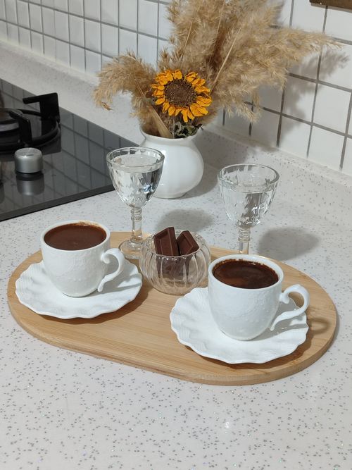 Free Elegant indoor coffee setup with two cups, glasses, chocolate, and floral arrangement. Stock Photo