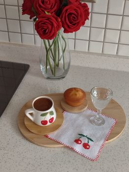 Charming breakfast scene with coffee, muffin, and roses on a kitchen countertop.
