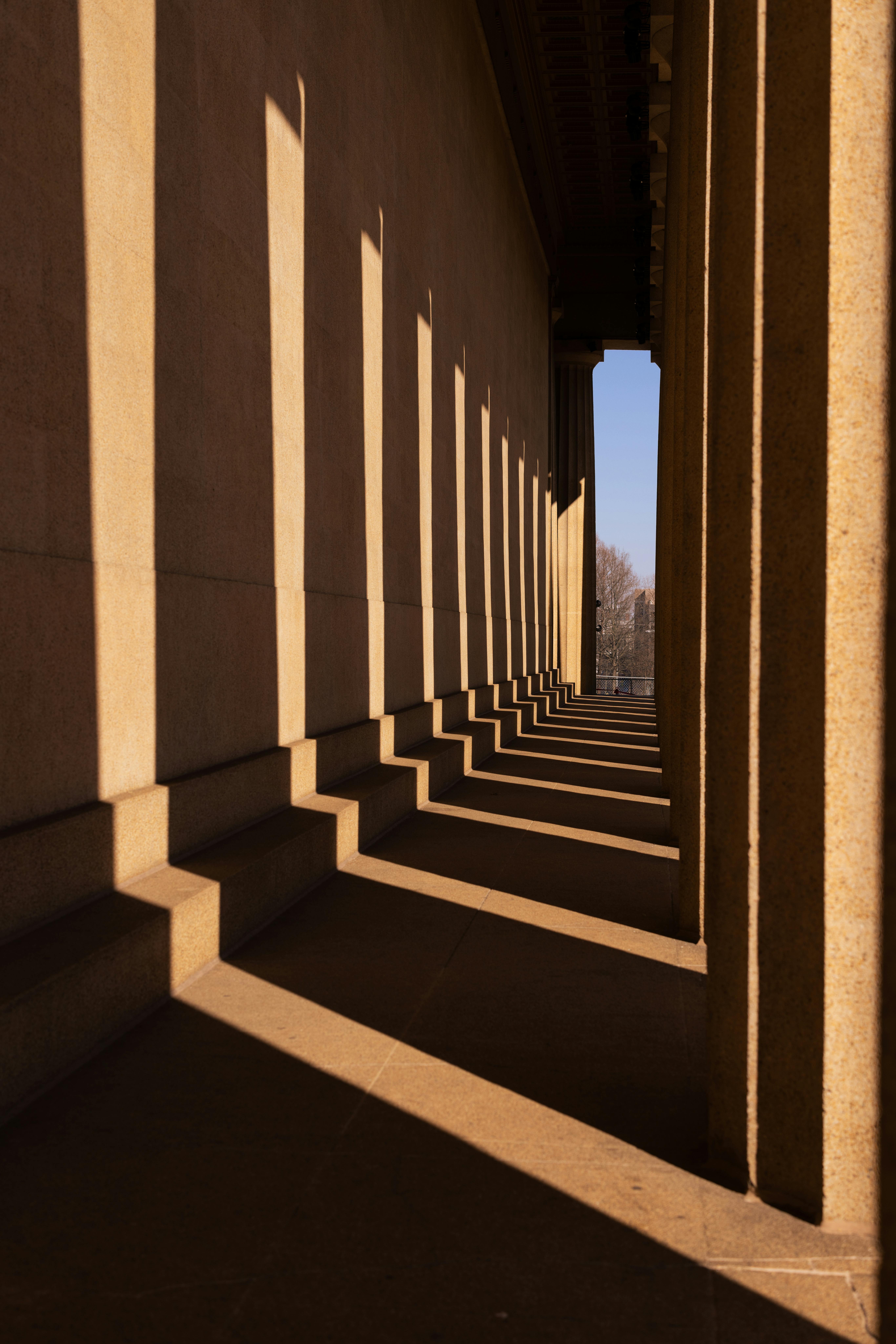 Kostenlos Entdecken Sie die dramatischen Schatten, die von klassischen Säulen in dieser Architekturaufnahme geworfen werden. Stock-Foto