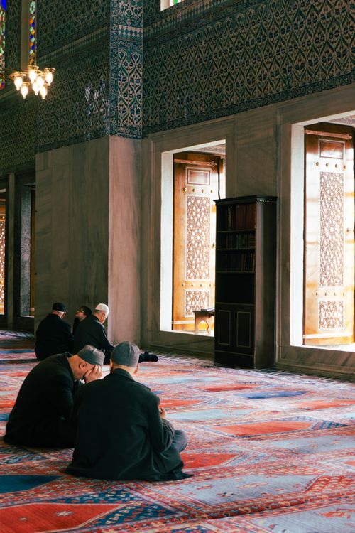 Free Men in traditional attire praying inside a beautifully decorated mosque in İstanbul. Stock Photo