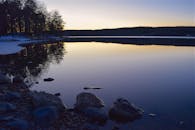 黄昏时分，宁静的湖面与岩石岸倒映着衰落的光，构成一幅平静的景象