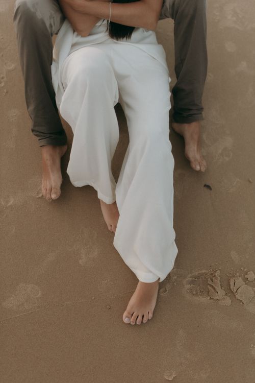 Free Couple sitting closely on a sandy beach, showcasing relaxation and intimacy. Stock Photo