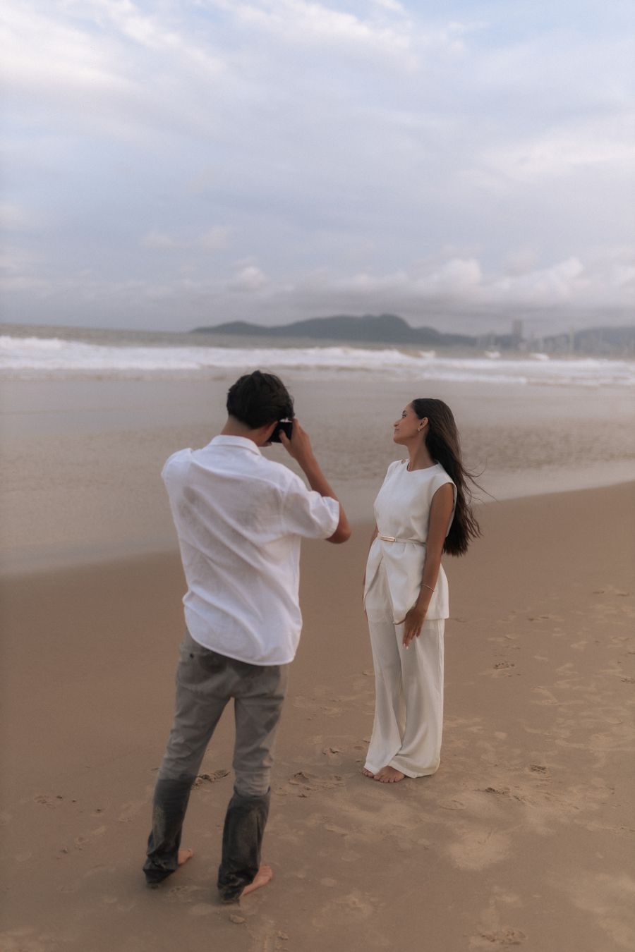 ผู้หญิงแต่งเดรสสีขาวถ่ายรูปริมทะเล
