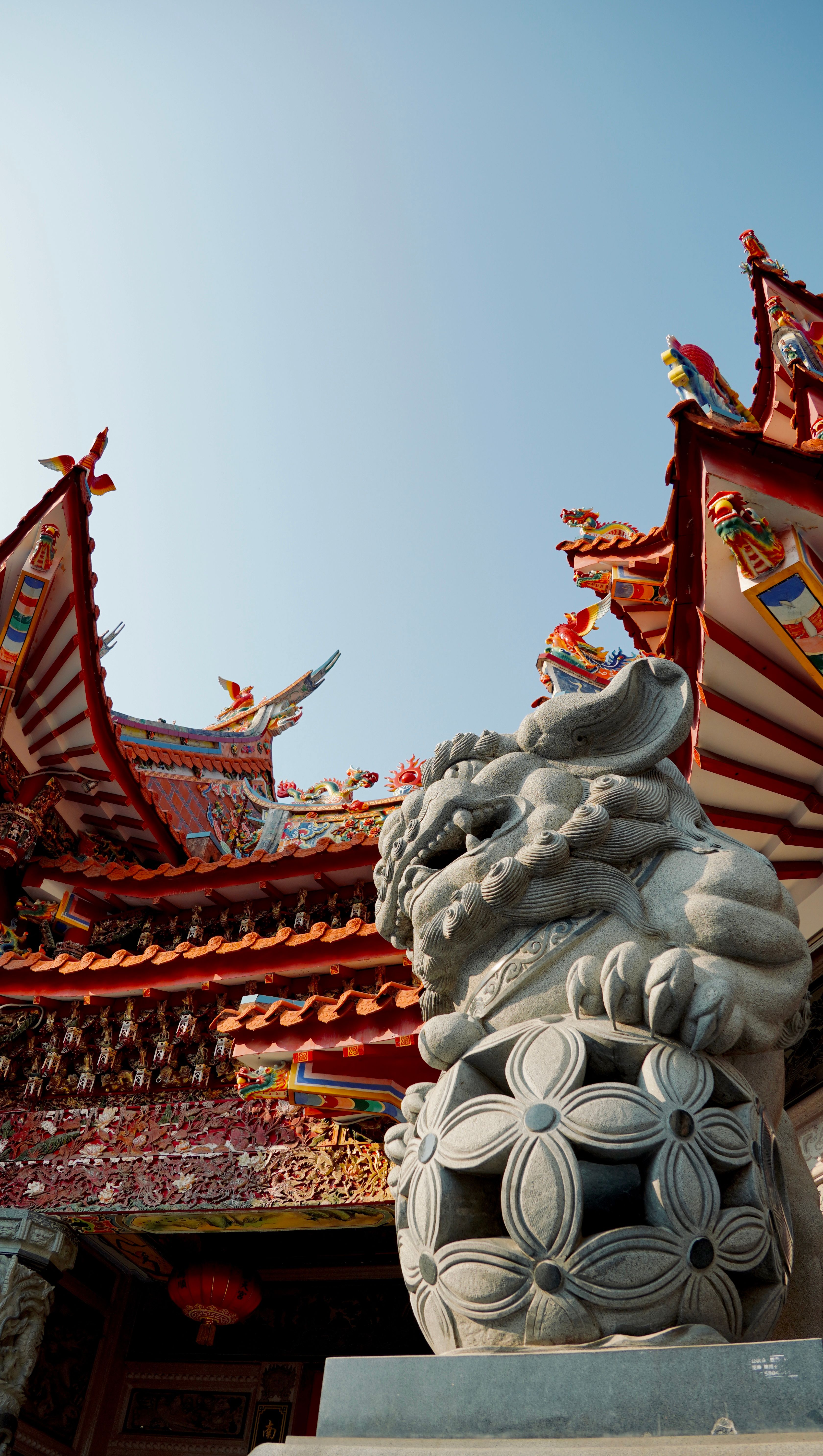 Ornate Temple Rooftop with Stone Guardian Lion Statue · Free Stock Photo
