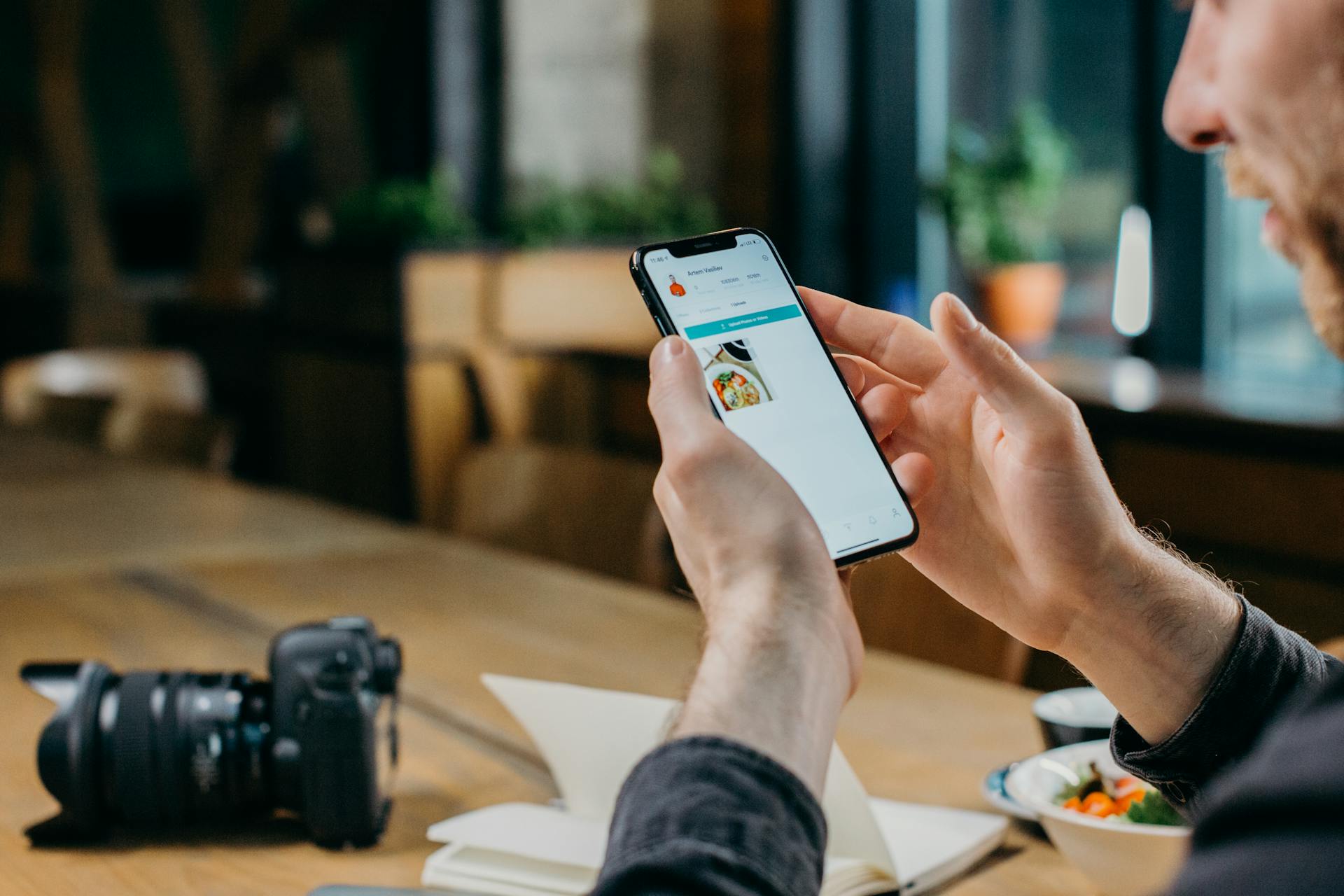 Man using smartphone in modern workspace, focusing on screen content.