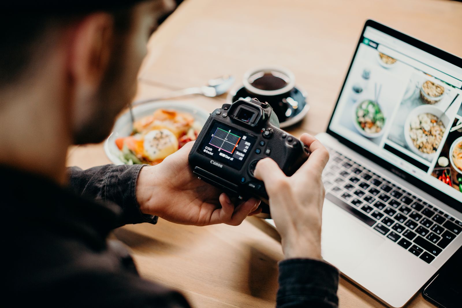A photographer reviewing camera settings while working on a laptop