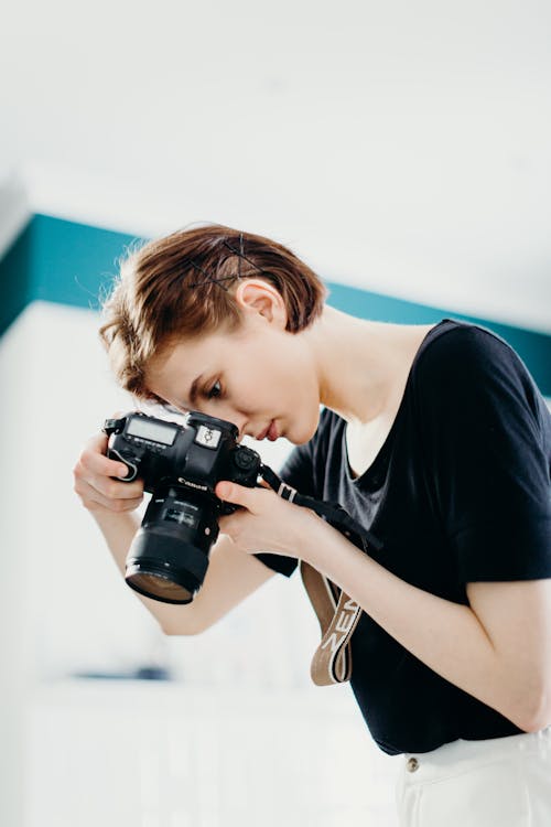 Woman In Black Top Memegang Kamera Dslr Hitam