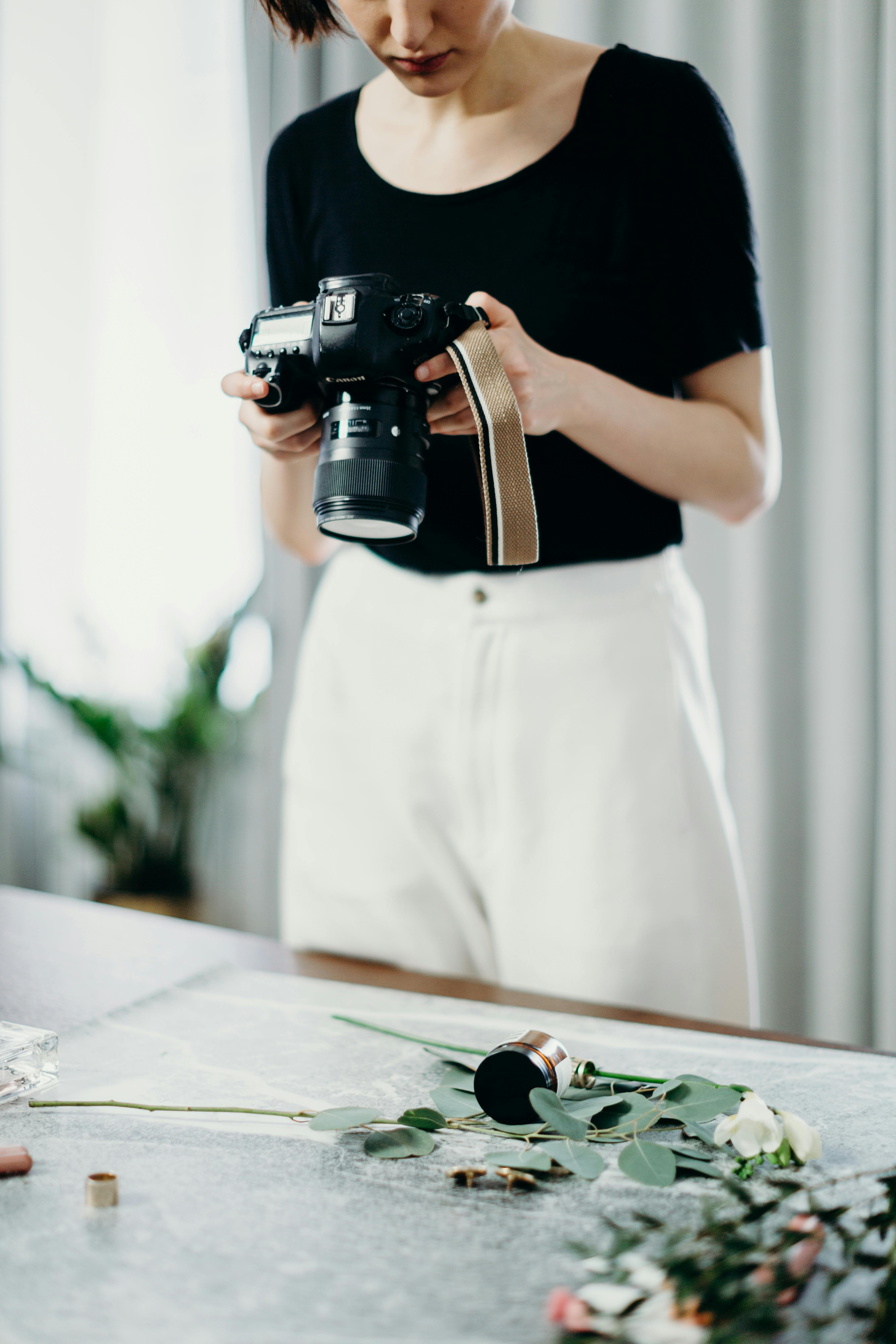 A woman photographs a floral setup indoors, focusing on creative photography.