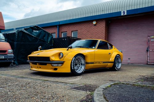 Free Vintage yellow Datsun 240Z parked outside a garage in Southampton, UK, showcasing automotive classic style. Stock Photo