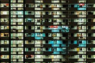 现代化公寓楼的街景中，亮着灯的窗户展现出城市生活