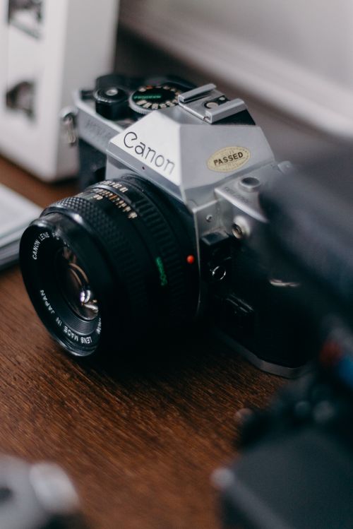Free A detailed look at a classic vintage film camera placed on a wooden desk. Stock Photo