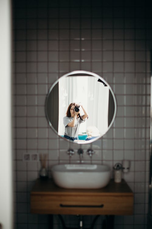 Selective Focus Photography of Woman Taking Photo Reflecting on Mirror