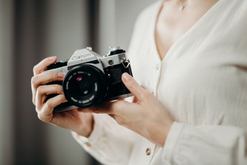 Free Close-up of a woman holding a vintage Canon film camera, emphasizing timeless photography. Stock Photo