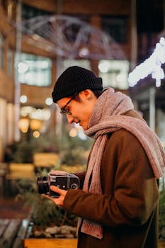 一名戴着无檐帽的男子在夜间带着老式相机探索城市