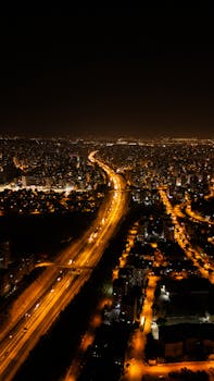 A mesmerizing aerial view of a cityscape at night, highlighting illuminated highways and buildings under a starry sky.